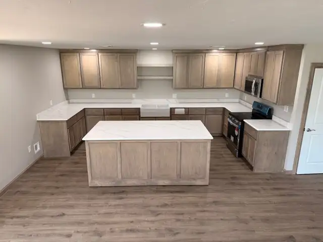 Large open kitchen with gray-washed cabinets, white countertops and a center island